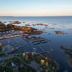 Aerial view of a coastal village with marina, boats, and surrounding islands.