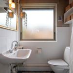 Badezimmer mit Waschbecken, Toilette und Fenster mit Milchglas.