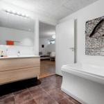 Badezimmer mit Badewanne, Waschbecken und Wandkunst.