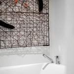 Bad mit weißen Wänden, Badewanne und Wanddekoration aus Draht.