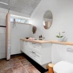 Badezimmer mit Dusche, Waschbecken und Toilette. Holzoberfläche und Spiegel.