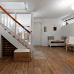 Eingangsbereich mit Treppe, Sitzgelegenheit und Holzboden.