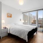Schlafzimmer mit Doppelbett, Kleiderschrank und Blick auf Terrasse
