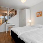 Schlafzimmer mit Bett, Schrank und Spiegelwand. Holzboden und Wandbild.
