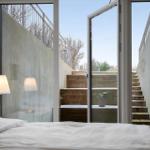 Schlafzimmer mit Blick auf Holztreppe und Außenbereich.