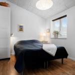Schlafzimmer mit Bett, Kleiderschrank und Fenster.