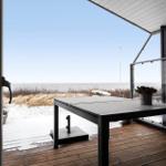Terrasse mit Tisch und Blick aufs Meer und Dünen.
