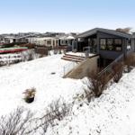 Moderne Villa mit Terrasse und Schneeflächen. Mehrere Kanus stehen im Garten.