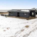 Modernes Haus mit Schnee, Blick auf Meer und Himmel.