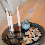 Drei brennende Kerzen, Lavendel und Muscheln auf einem Metalltablett.