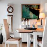 Esszimmer mit Tisch, Stühlen, Wanduhr und Gemälde.