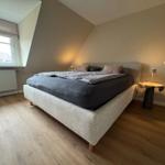 Schlafzimmer mit Dachschräge, Bett, Nachttisch und Fenster.