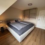 Schlafzimmer mit Doppelbett, Schrank und Holzboden.