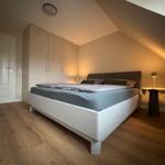 Schlafzimmer mit Dachschräge, weißem Bett und Holzboden