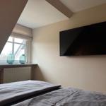 Schlafzimmer mit Dachschrägen, Fenster und Wandfernseher.