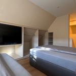 Schlafzimmer mit Bett, Kleiderschrank und Fernseher.