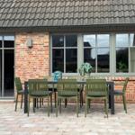 Außenbereich mit Tisch und Stühlen vor einem Backsteinhaus mit Fenstern.