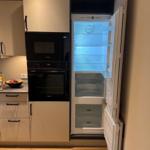 Küche mit Kühlschrank, Backofen und Mikrowelle