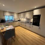 Küche mit Essbereich, Holzboden und modernen Schränken.