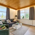 Wohnzimmer mit Sofa, Sesseln und Fenstern zum Blick auf die Berge.