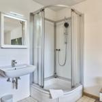 Badezimmer mit Duschkabine, Waschbecken und Spiegel.