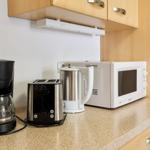 Küchenzeile mit Kaffeemaschine, Toaster, Kaffeemaschine und Mikrowelle.