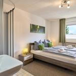 Schlafzimmer mit Doppelbett, Fenster und integriertem Bad.