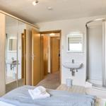 Schlafzimmer mit Dusche, Waschbecken und Kleiderschrank. Durchgang zu weiteren Räumen.