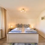 Schlafzimmer mit Doppelbett, Fenster und Nachttischen.