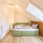 Schlafzimmer mit Dachschräge, Dachfenster und grünem Bett.