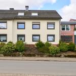 Haus Bergfried mit Vorgarten und Garage. Zwei Stockwerke mit Fenstern und Dachfenstern.