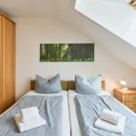 Zimmer mit zwei Betten, Schrank, Nachttisch und Dachfenster.