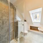Badezimmer mit Dusche, Toilette und Waschbecken unter Dachschrägen