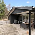 Terrasse mit Sitzgruppe, Grill und Blick in den Wald.