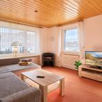 Wohnzimmer mit Sofa, Fernseher und Holzdecke.