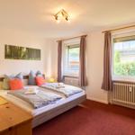Schlafzimmer mit Doppelbett, Fenster und Holztisch.