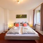 Schlafzimmer mit Doppelbett, Nachttischen und Fenster.
