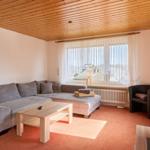 Wohnzimmer mit Sofa, Couchtisch und Fernseher. Holzdecke und Fenster mit Blick.