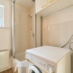 Badezimmer mit Dusche, Waschmaschine und Fenster