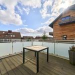 Terrasse mit Tisch und Pflanze, Blick auf Wohnhäuser und Himmel.
