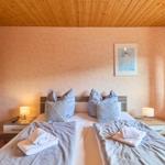 Zimmer mit Doppelbett, Nachttischen und Holzdecke.