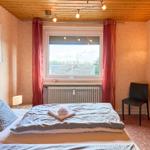 Schlafzimmer mit Bett, Fenster, Stuhl und Decke.