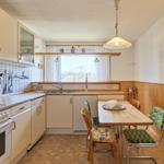Küche mit Essbereich, Fenster, Spüle und Küchenschränke.