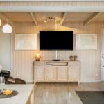 Wohnzimmer mit Fernseher, Holzwand und Essbereich.