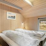 Schlafzimmer mit Holzwand, Bett und Fensterblick.