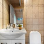 Badezimmer mit Waschbecken, Spiegel und Toilette. Fliesenwand mit dekorativer Bordüre.