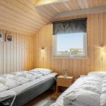 Zwei Betten in einem Holzhauszimmer mit Fenster und Nachttisch.