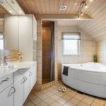 Badezimmer mit Badewanne, Dusche und Waschbecken unter Holzdecke.