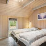 Schlafzimmer mit Holzwand und Bett. Fenster zeigt Außenbereich.