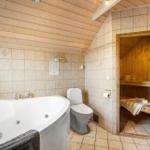 Bad mit Whirlpool, Toilette und Sauna im Hintergrund.
